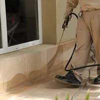 General pest control technician spraying exterior perimeter around a home in Dallas, TX