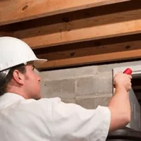 Termite inspection technician checking a basement wall and framing for termite activity in Dallas, TX